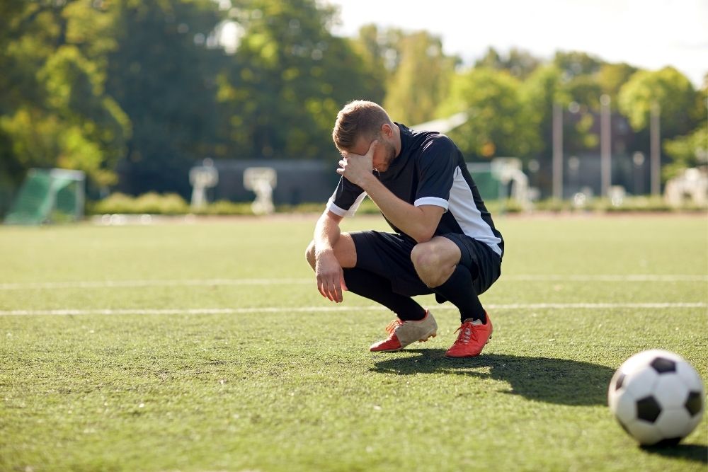 Soccer player grab his face because of missing opportunity
