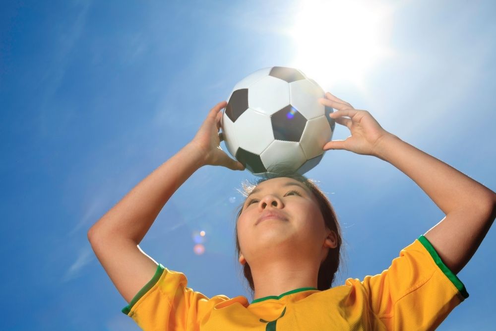 Soccer player hold the soccer ball on her head