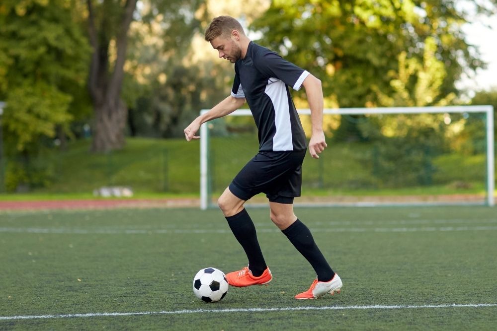 Soccer player push the ball with his left foot