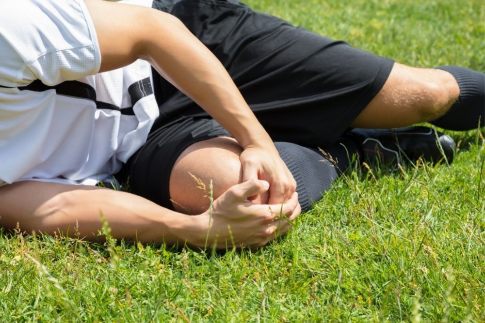 a soccer player painfully holds his knee