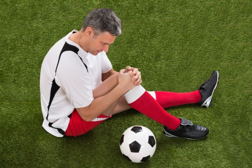 a soccer player sits and holds his knee