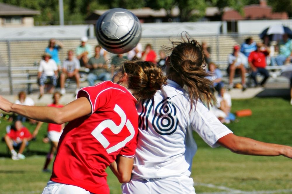 female soccer player using her head to block a goal
