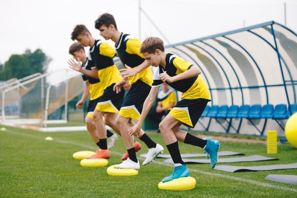 four soccer players are doing training on soccer field