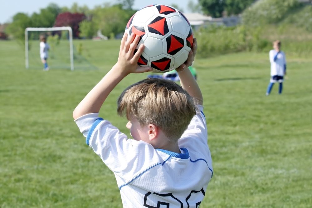 kid holds the ball firmly above his head