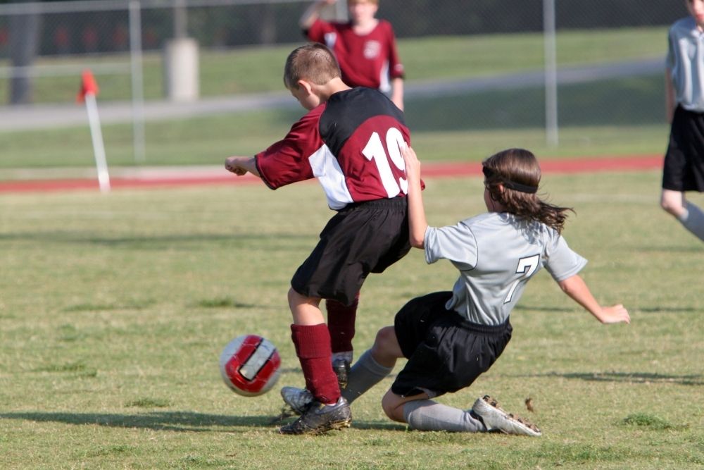 kid soccer player tacking a ball agressively