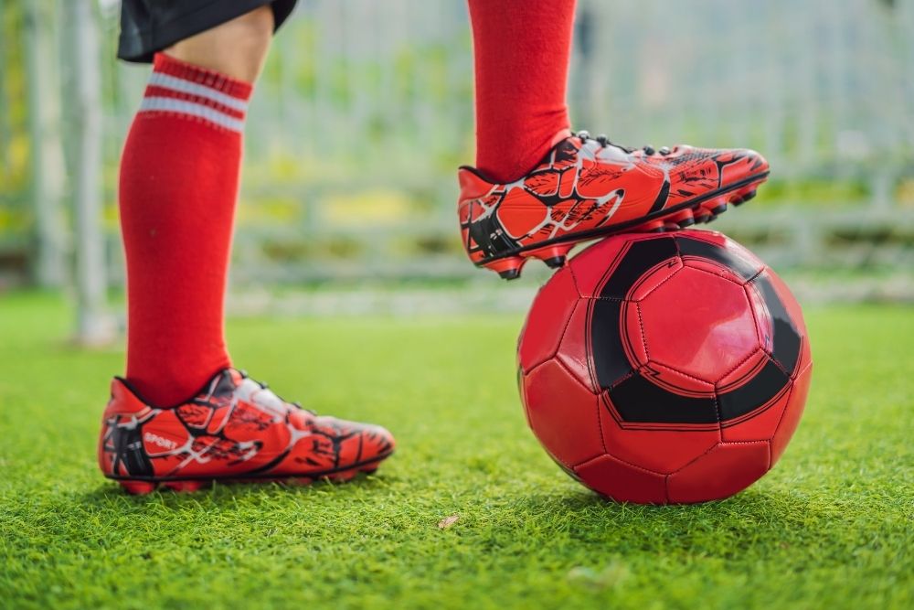 man putting his foot on the red soccer ball