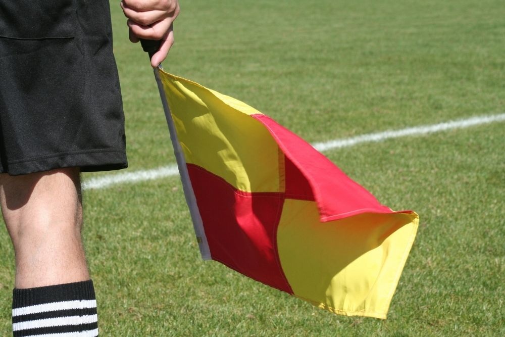referee holding a flag with red and yellow colors