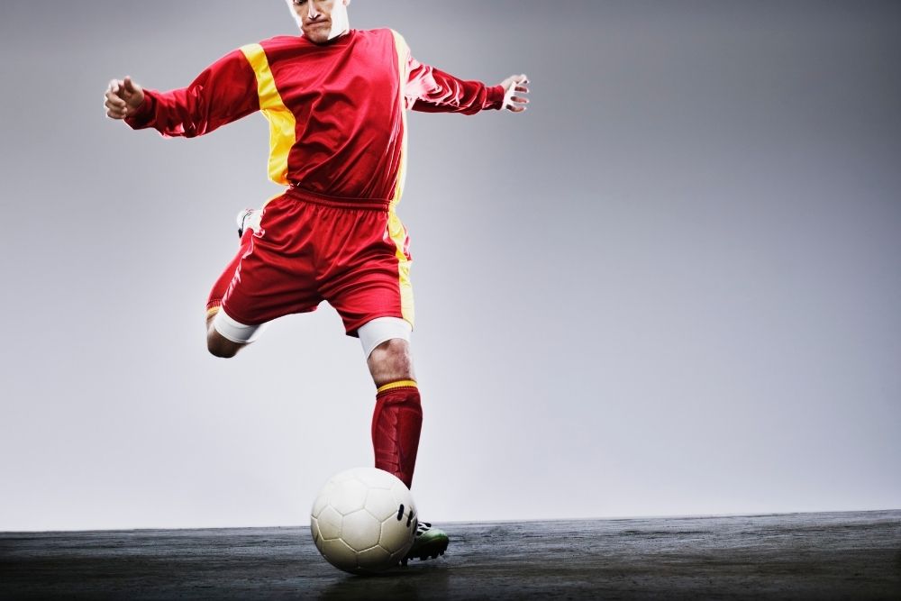 soccer player in red uniform kicking a ball