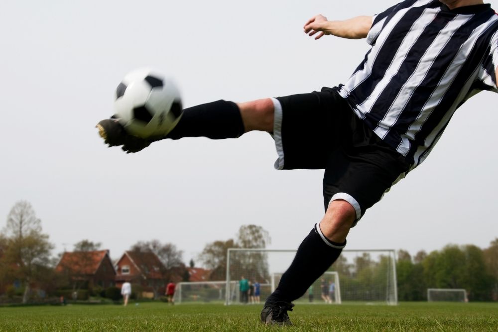 soccer player in stripe jersey shooting a ball