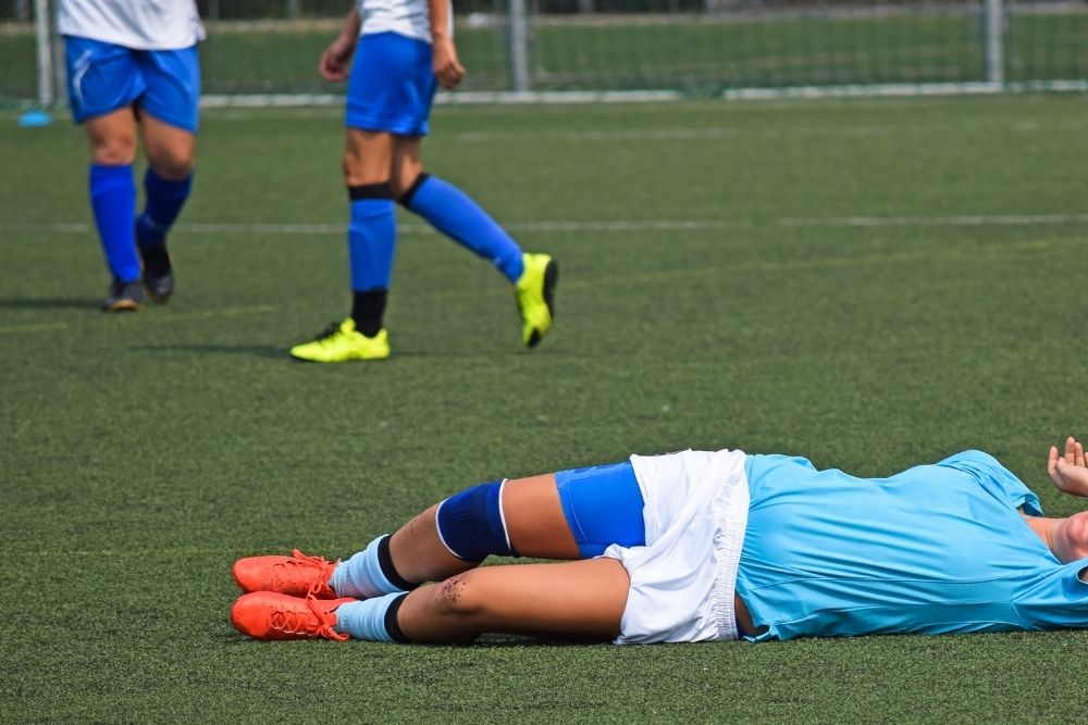 soccer player lying down on the pitch