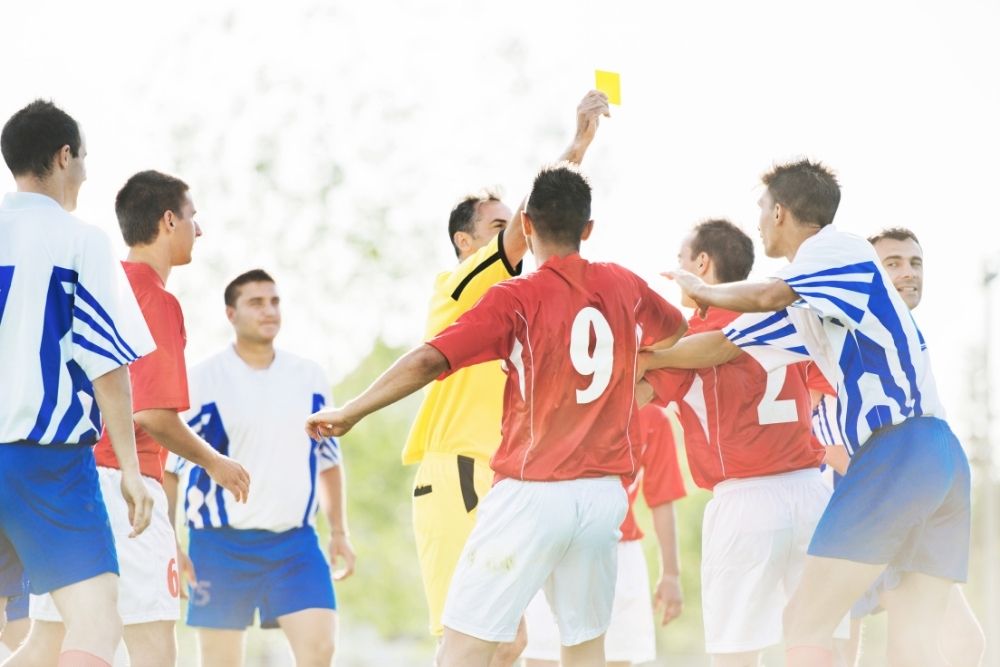 soccer referee giving a yellow card after a foul