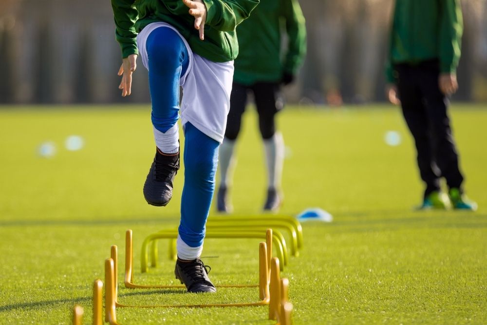 Soccer player practicing with hurdle
