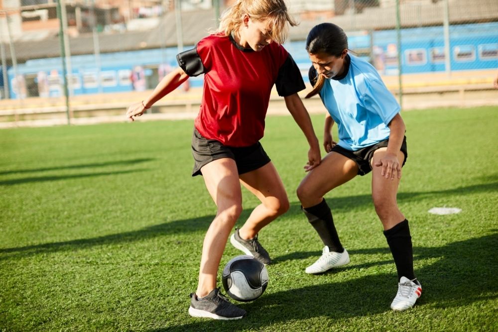 female soccer player dribbling a ball through opponent