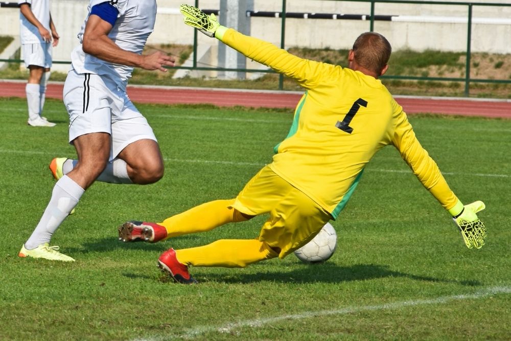 soccer goalkeeper in yellow catching a ball