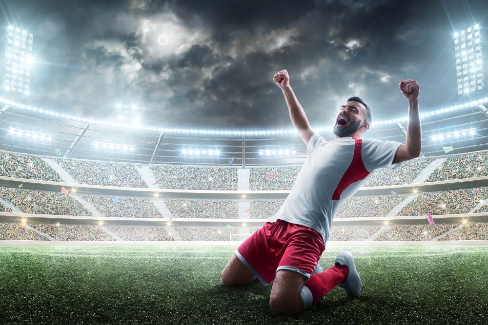 soccer player kneeling for a victory at the stadium with bright light