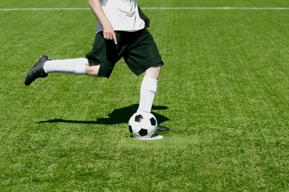 soccer player swings his right foot to kick soccer ball