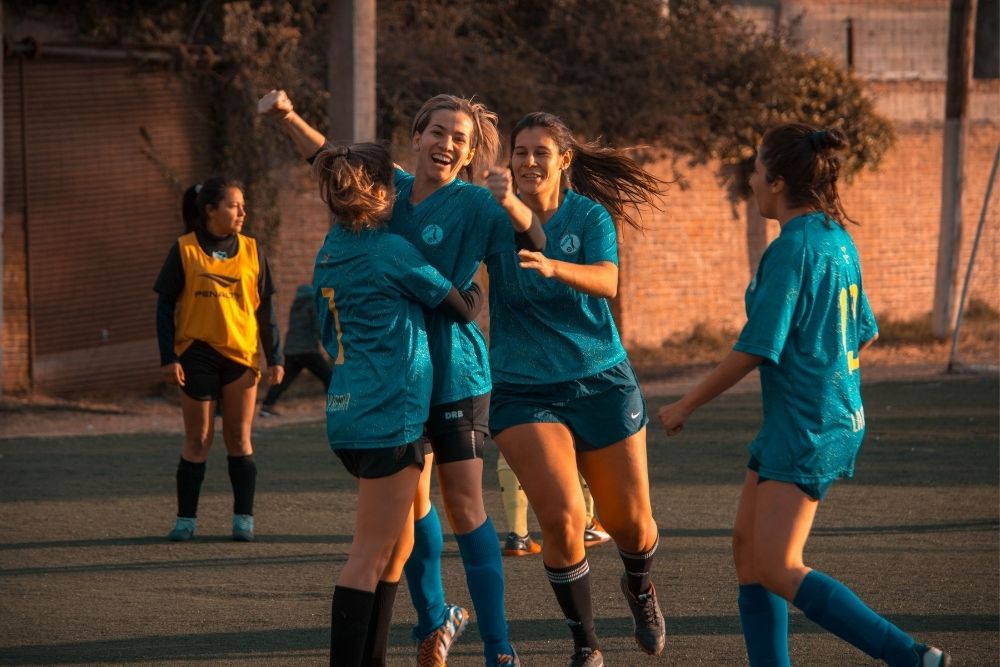 tall female soccer players in blue hugging for cheering a goal