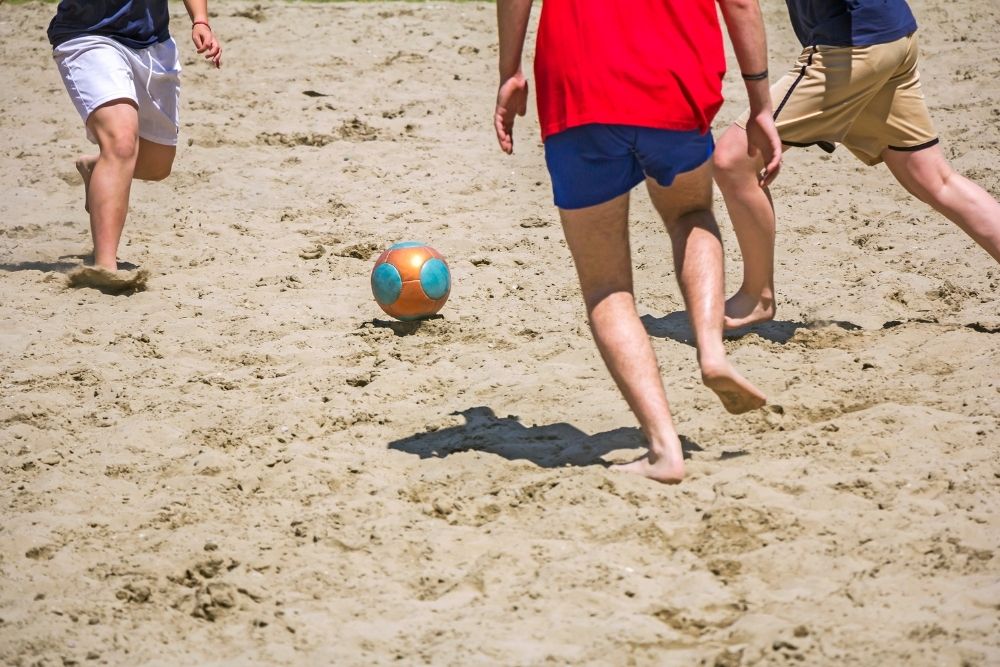three players in beach soccer match