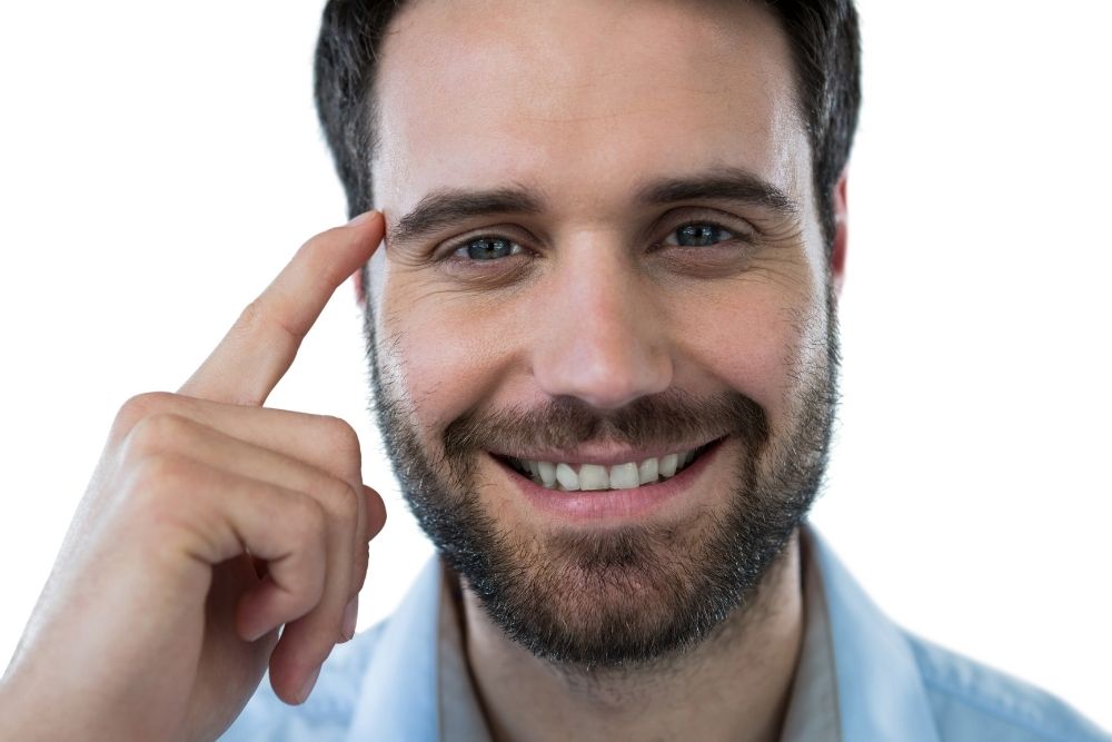 man smiling and point at his head