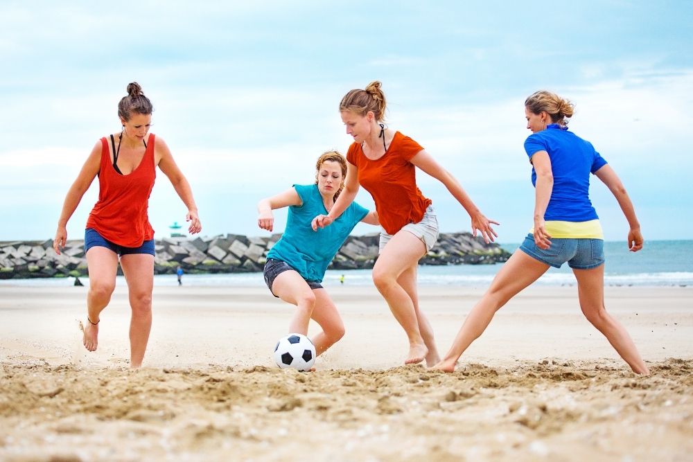 four girls playing beach soccer