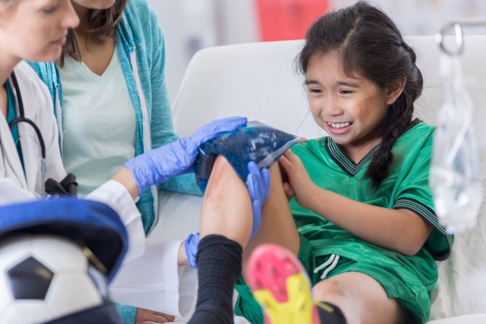 doctor puts an icepack on the knee of a kid