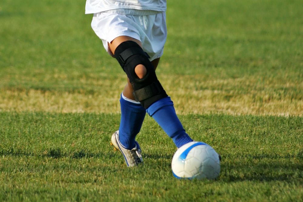 Soccer player wearing knee brace dribbling the ball