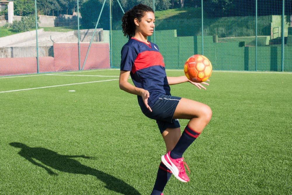 a female soccer player is bouncing a soccer on her knee