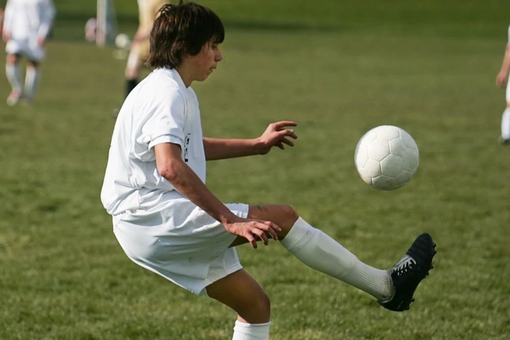 a kid juggles a soccer ball