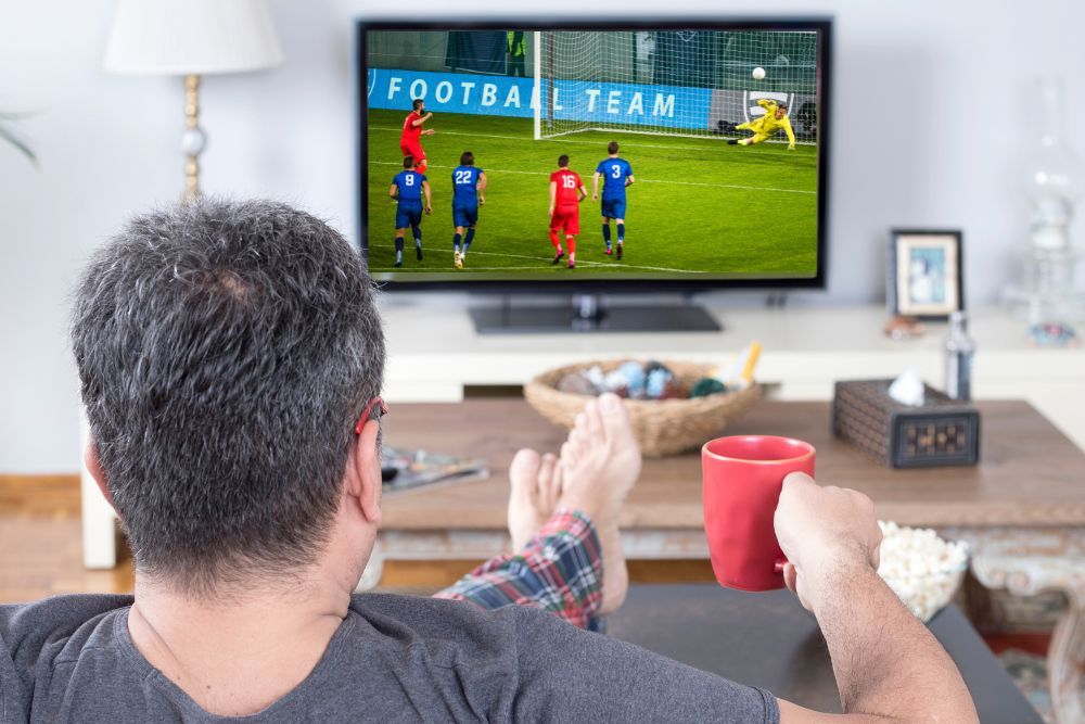 man watches a soccer match on TV to learn their tactics