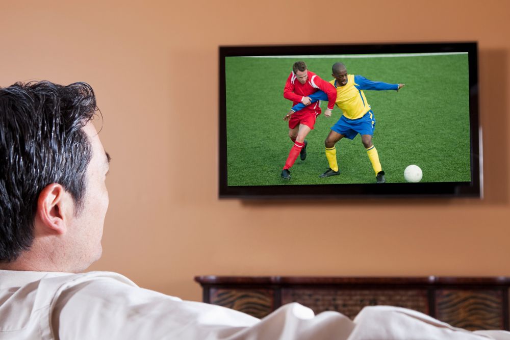 man watches man marking technique in soccer on TV