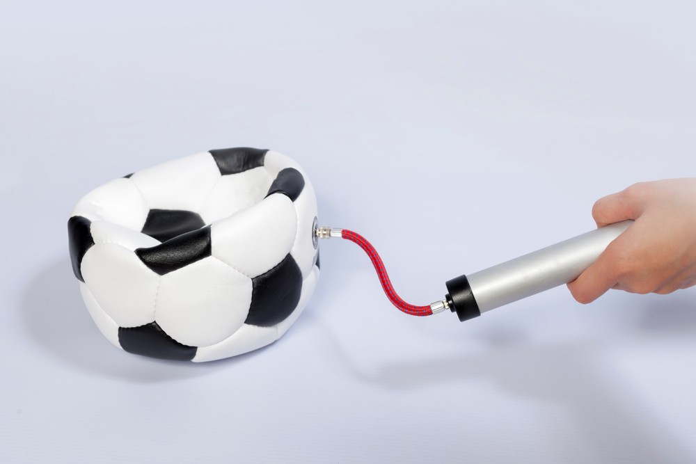 a man deflates soccer ball using the ball pump